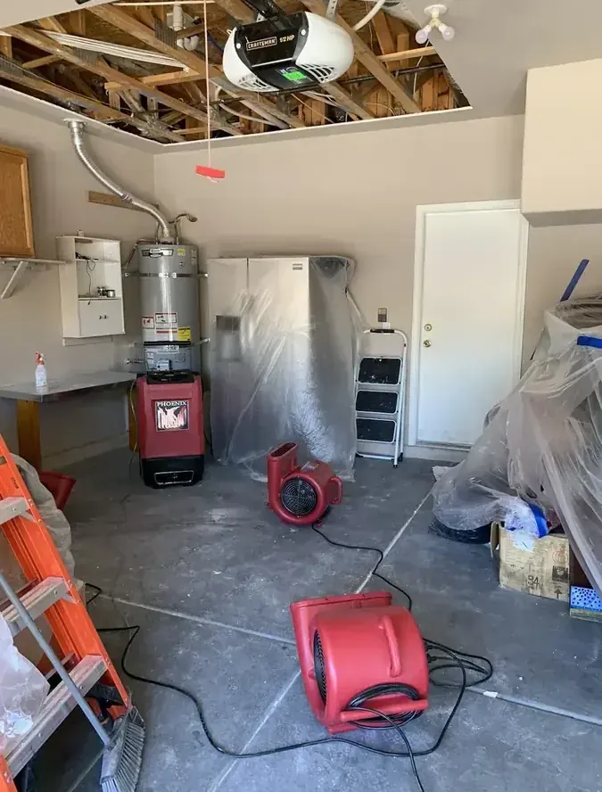 Drying equipment stands in a garage beneath an opened ceiling