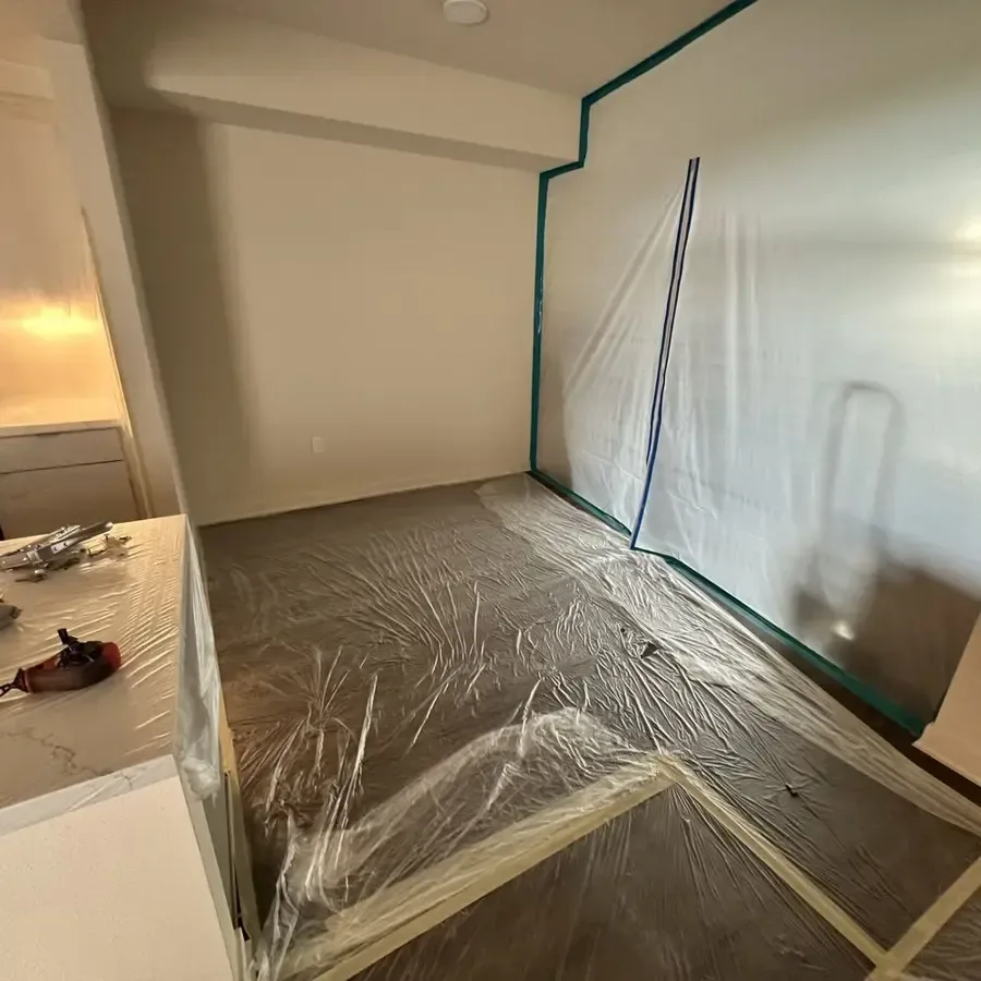 Plastic sheeting encloses a room during controlled water damage drying work